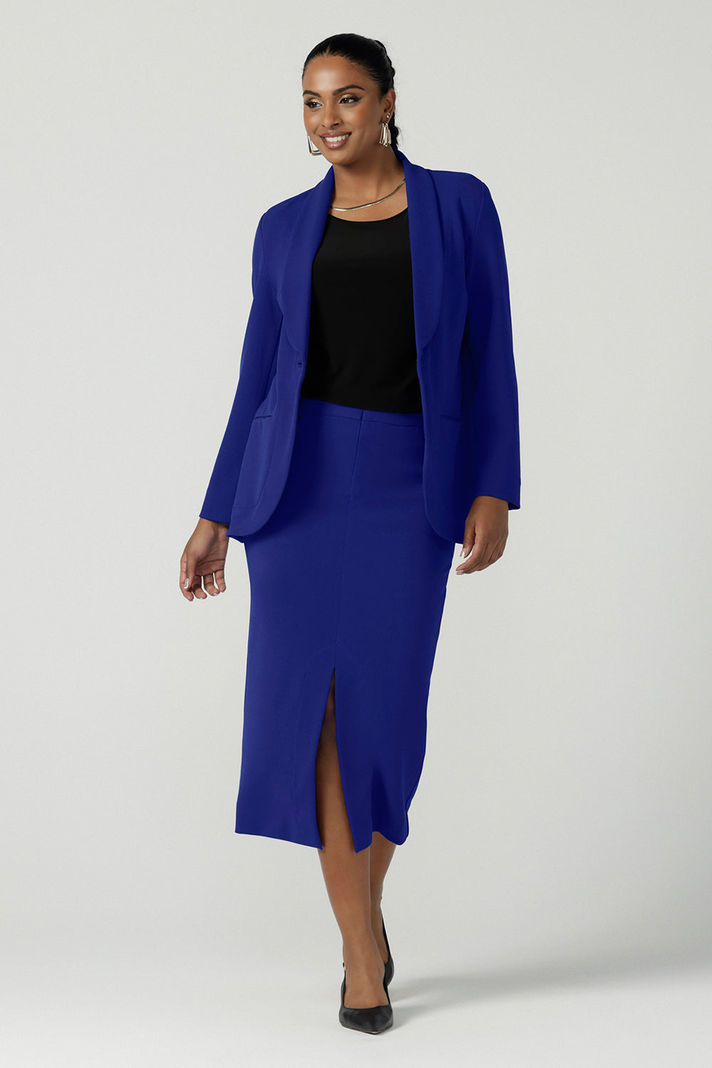 A size 10 woman wears the Aaron Mid Skirt in Cobalt Crepe back with the Black Ziggy Top. Made in Australia for women size 8-24. Comfortable corporate wear for women. Suit Sets in Cobalt. Easy care material. Petite to Plus Size women. Styled back with the Merit Blazer in Cobalt.