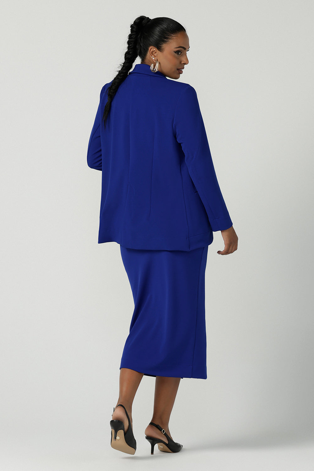 Back view of a size 10 woman wears the Aaron Mid Skirt in Cobalt Crepe back with the Black Ziggy Top. Made in Australia for women size 8-24. Comfortable corporate wear for women. Suit Sets in Cobalt. Easy care material. Petite to Plus Size women. Styled back with the Merit Blazer in Cobalt.