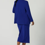 Back view of a size 10 woman wears the Aaron Mid Skirt in Cobalt Crepe back with the Black Ziggy Top. Made in Australia for women size 8-24. Comfortable corporate wear for women. Suit Sets in Cobalt. Easy care material. Petite to Plus Size women. Styled back with the Merit Blazer in Cobalt.