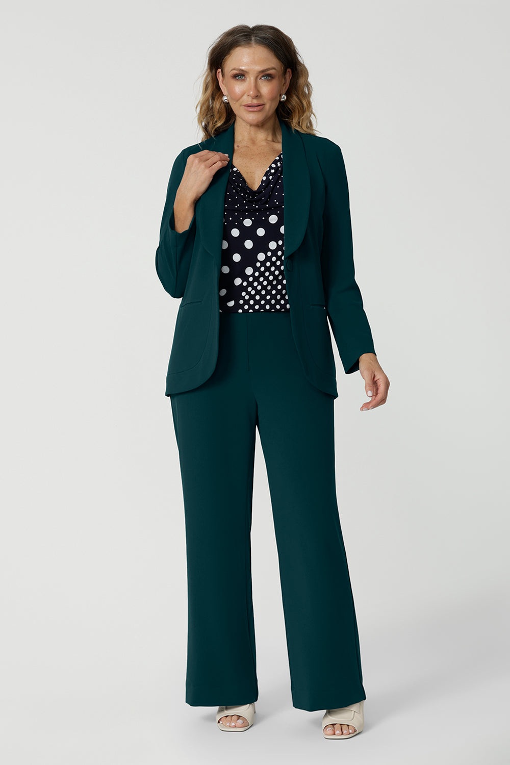 Showing good workwear for over 50s women, a Green scuba crepe suit is worn with a navy and white spot print jersey top. This longline women's work blazer and wide leg work pants are made in Australia by Australia and New Zealand women's clothes brand, Leina & Fleur. Available to shop in sizes 8 to 24, this is workwear for plus size to petite height women. 