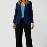 A size 10 woman wears the Merit Blazer in Sailor Scuba crepe fabric. A softly tailored blazer with lapel collar and full length sleeves. Button front and pockets. Made in Australia for women size 8-24. Styled back with a Eddy cami in Mineral and Black Monroe Pant. 