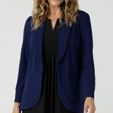 A size 10 woman wears the Merit Blazer in Sailor Scuba crepe fabric. A softly tailored blazer with lapel collar and full length sleeves. Button front and pockets. Made in Australia for women size 8-24.