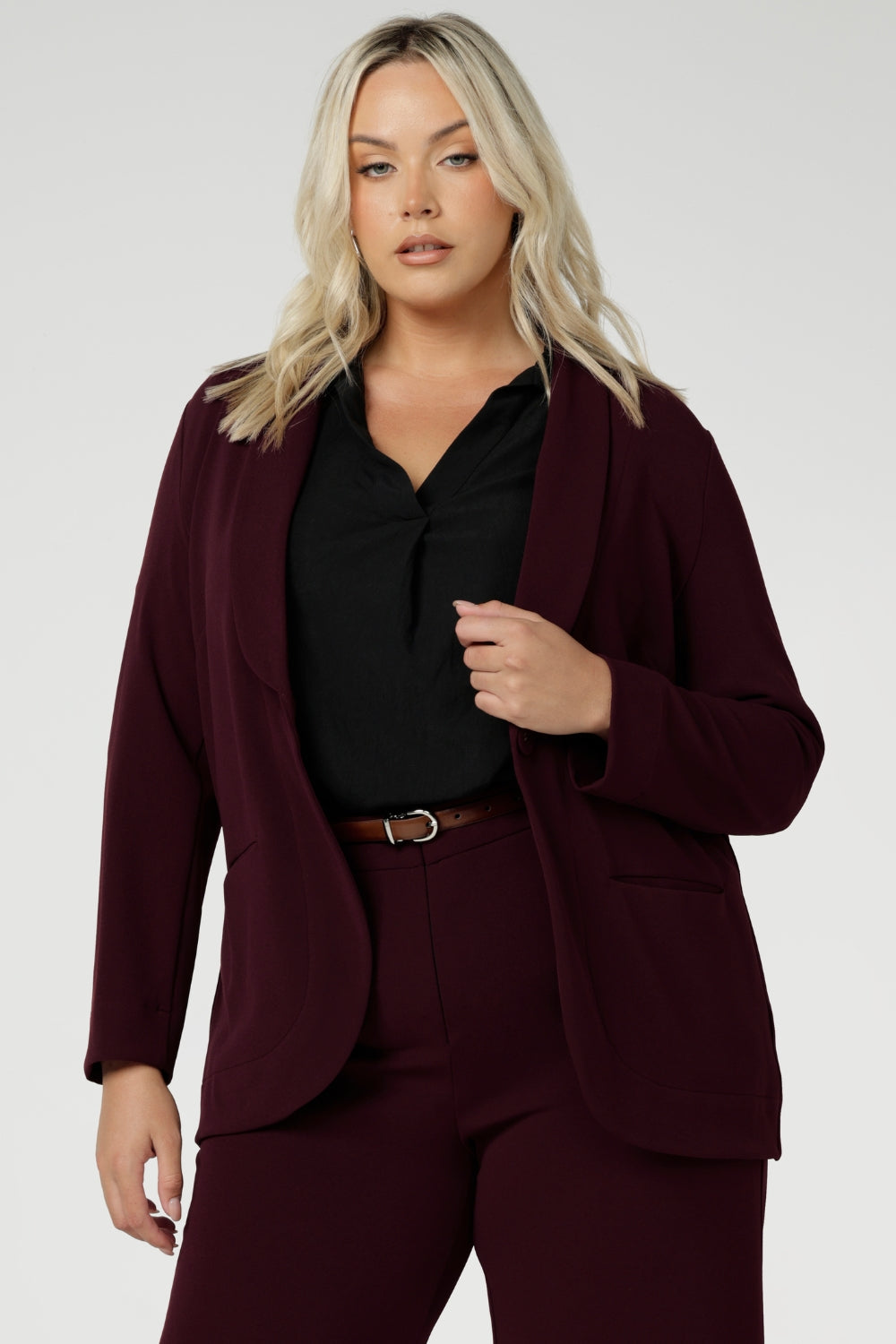 Merit is a tailored and light weight woman's workwear blazer that offers elevated style. Size 18 woman wears workwear blazer in deep wine colour, crafted from quality scuba crepe fabric. Long blazer offers full body stretch and comfort. Australia made by Leina & Fleur in sizes 8-24.