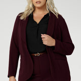 Merit is a tailored and light weight woman's workwear blazer that offers elevated style. Size 18 woman wears workwear blazer in deep wine colour, crafted from quality scuba crepe fabric. Long blazer offers full body stretch and comfort. Australia made by Leina & Fleur in sizes 8-24.