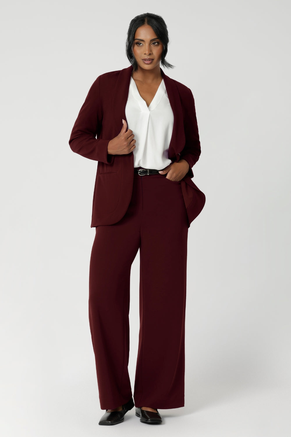 This women's workwear blazer in a rich wine colour is crafted from a luxe Scuba Crepe Jersey fabric, offering a soft textured feel with a hint of stretch for comfort and flexibility. Available in sizes 8-24. Size 10 model wears blazer with matching wide leg pants for the perfect suiting outfit.