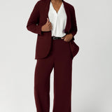 This women's workwear blazer in a rich wine colour is crafted from a luxe Scuba Crepe Jersey fabric, offering a soft textured feel with a hint of stretch for comfort and flexibility. Available in sizes 8-24. Size 10 model wears blazer with matching wide leg pants for the perfect suiting outfit.