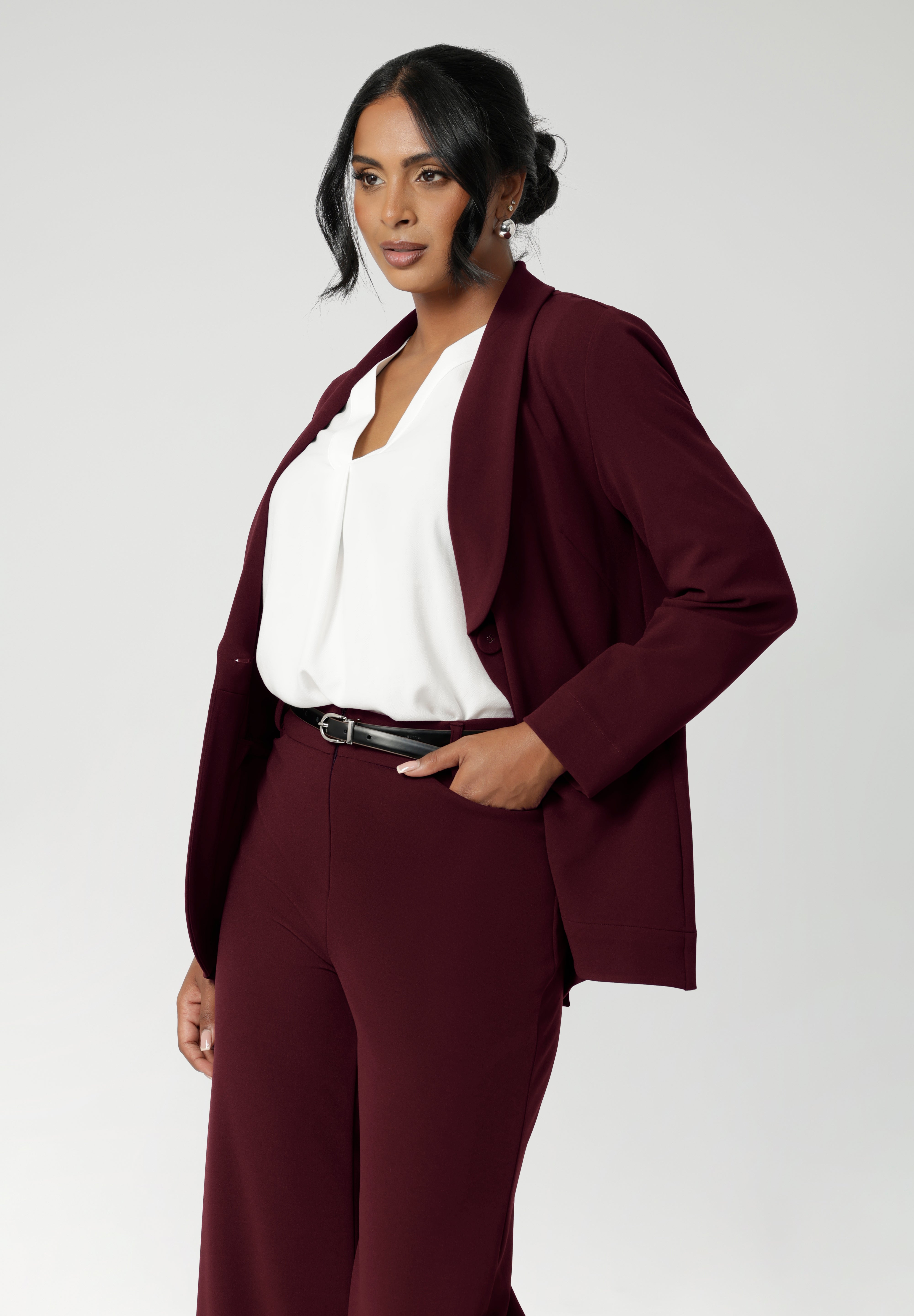 Merit is a tailored and light weight woman's workwear blazer that offers elevated style. Size 12 woman wears workwear blazer in deep wine colour, crafted from quality scuba crepe fabric. Long blazer offers full body stretch and comfort. Australia made by Leina & Fleur in sizes 8-24.