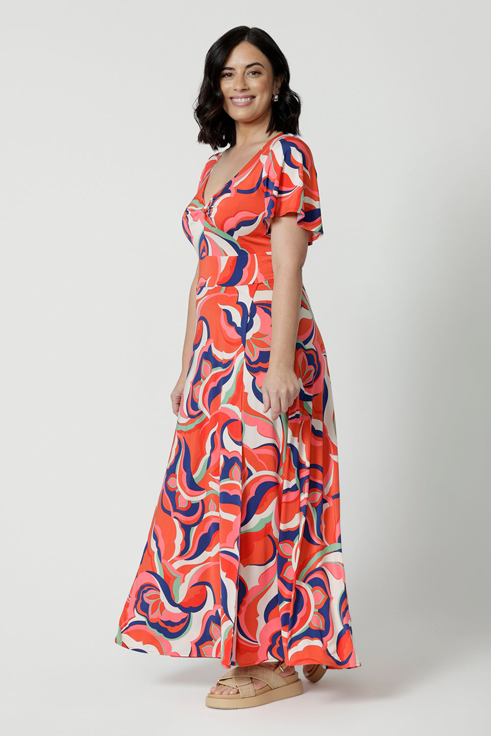 Side view of a good summer maxi dress for petite height women, this printed jersey dress has a twist front bodice and flutter sleeves. A dress for cruise holidays and resort style, this maxi dress is easy-care and crease-resistant. Made in Australian by Australian and New Zealand women's online clothes brand, Leina & Fleur, shop their cruise wear fashions online in sizes 8 to 24.