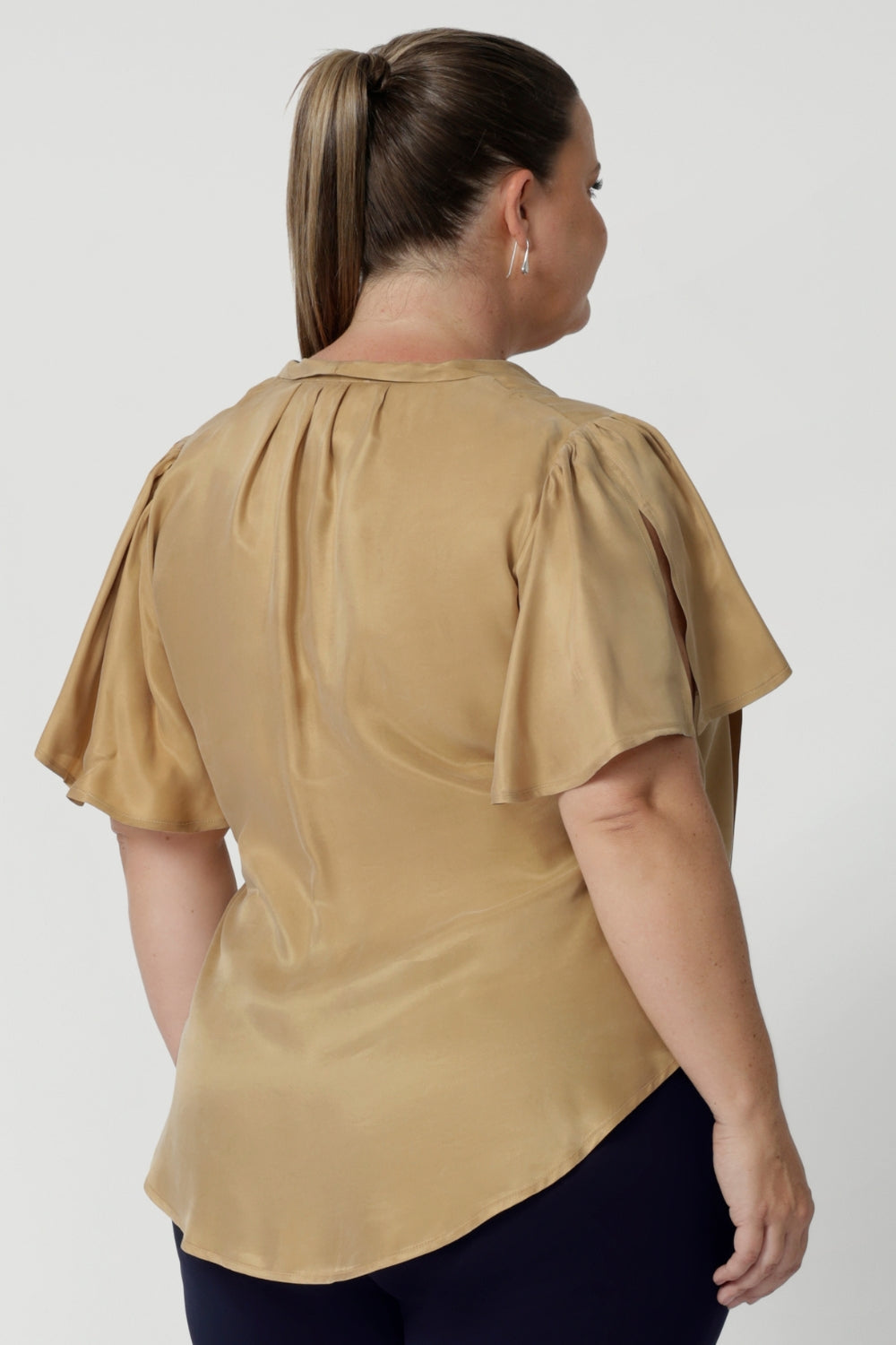 Image shows plus size woman wearing evening blouse, featuring a shirttail hemline. This women's blouse is versatile enough to be tucked into skirts or trousers for a polished look. Available in sizes 8-24 and exclusively online at Leina & Fleur, this shirt is the perfect addition to any wardrobe.