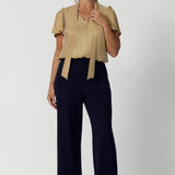 Workwear blouse seen on over 40's woman, offers endless mix-and-match possibilities with other pieces from our soft suiting or scuba collections. Neck ties are seen untied and the blouse untucked, creating a soft open tuxedo look. Michael Shirt in Gold is available in sizes 8-24 and in many colours and prints.