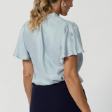 Made from a luxurious soft suede-touch Tencel fabric in a cool, serene Ice Blue colour. This women's blouse drapes beautifully on the body, creating a flattering and luminous effect. Breathable blouse features flutter sleeves with slits and shirttail hem.