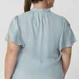 serene Ice Blue, this blouse drapes beautifully on the body, creating a flattering and luminous effect. Though the fabric has no stretch, its elegant drape moves gracefully with you, adding a touch of elevated style to any occasion. The shirttail hemline makes this blouse versatile enough to tuck into high-waisted pants or skirts for a polished office look or leave untucked for a more relaxed vibe.