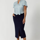 Available in sizes 8-24 and exclusively online at Leina & Fleur, the Michael Shirt in Ice Blue offers endless styling possibilities when paired with other items from our soft suiting collection. Size 12 woman wears blouse with neckties with midi navy skirt and brown kitten heels.  