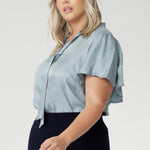 Light blouse, suede touch blouse features a V-neckline with adjustable neckties allows for a customisable fit, adding a feminine touch to the look. Size 18 woman wears her Micheal Shirt with neckties done up in a tie with a navy workwear midi skirt.