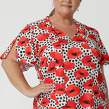 Woman wears printed top with short flutter sleeves that feature slits on the shoulders to add a soft, feminine touch, that move and flow with her every step. Bright poppy printed blouse matched her tangerine coloured pants perfectly.