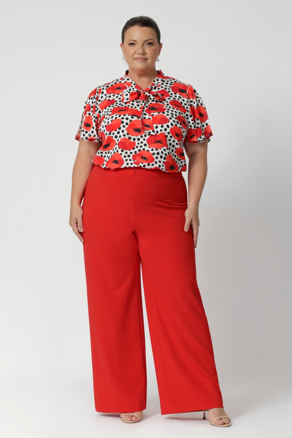 Plus size woman wears poppy printed shirt with tangerine coloured pants, for a vibrant office to evening outfit. Australian-made and available in sizes 8-24, the Michael Shirt offers both style and comfort for the women who wants versatility and elegance in their wardrobe.