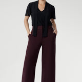 Woman wearing a black top with neck ties and high waisted wide leg pants. Perfect for the office, weekend escapes, or evenings out with friends.