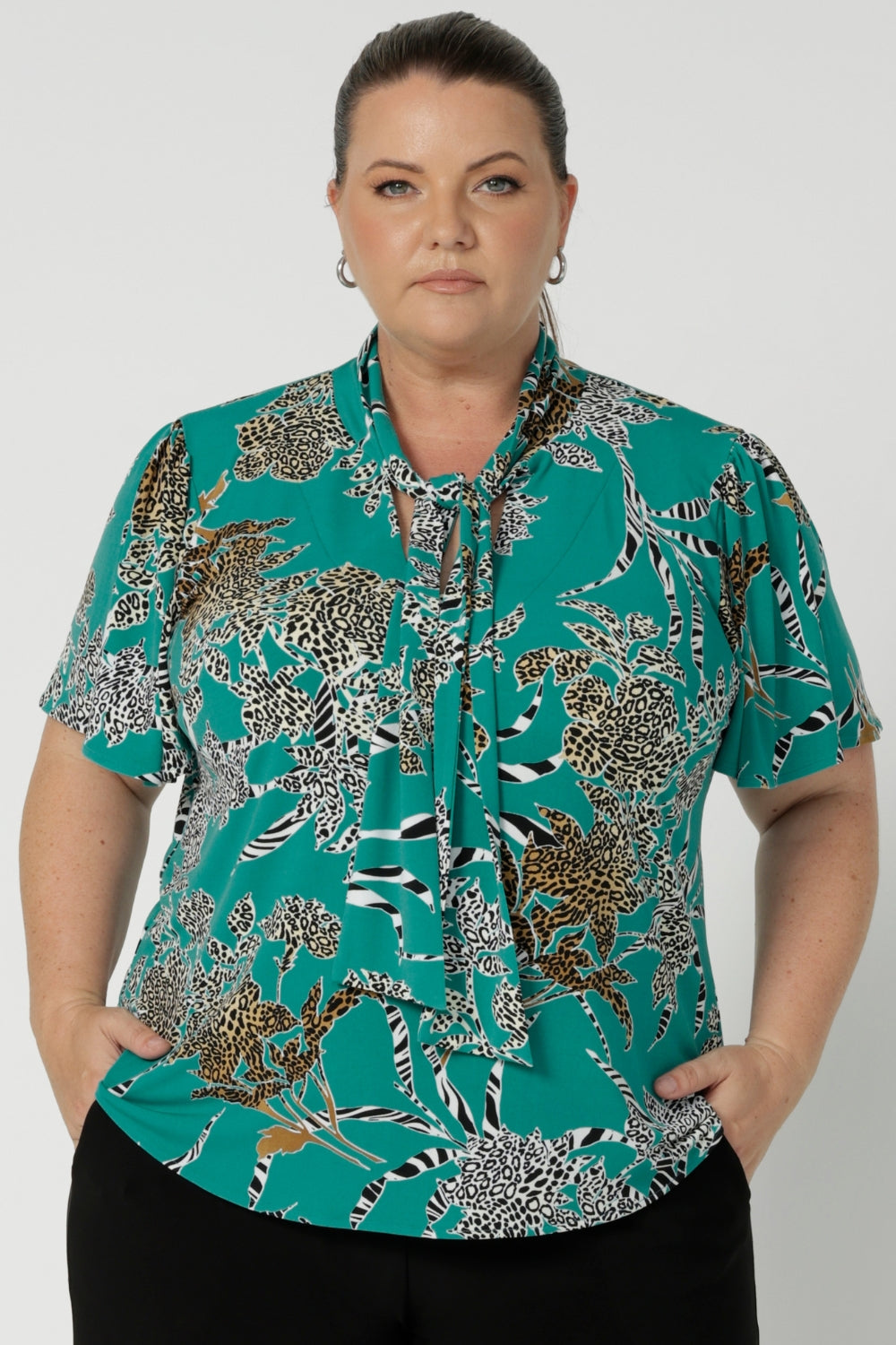 This short-sleeved top features a flattering cut and a unique neckline with tie details. The neck ties can be done up for added coverage or left undone for a more relaxed, open look, allowing you to customise the shirt to your comfort and style preferences. The sleeve features a slit detail that ads a soft feminine look to your ideal back to work piece. Available in sizes 8-24.