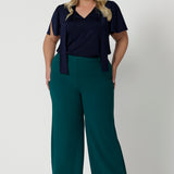 Showing good workwear for plus size women,  Green scuba crepe wide leg pants are worn with a navy jersey top. These wide leg work pants are made in Australia by Australia and New Zealand women's clothes brand, Leina & Fleur. Available to shop in sizes 8 to 24, this is workwear for plus size to petite height women. 