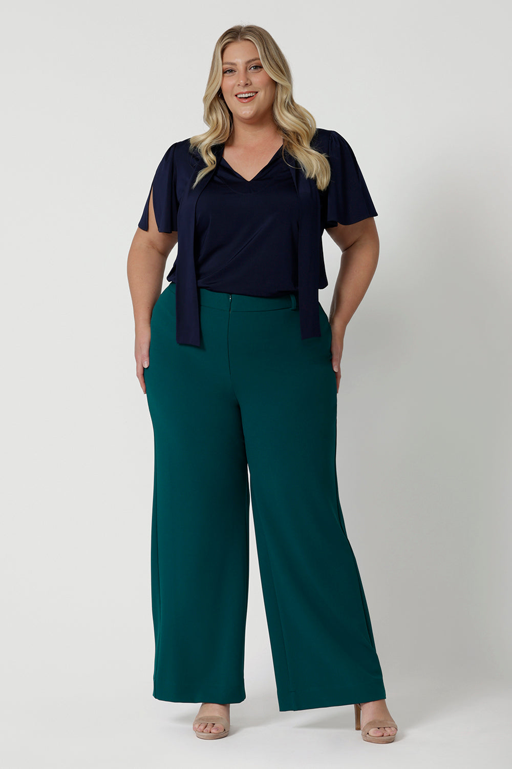 Full body front shot of plus sized woman wearing navy work wear blouse. This top is navy in colour and has been designed using high quality easy care dry touch jersey material. Garments are Australian made by Leina & Fleur for Australian and New Zealand woman. Leina & Fleur proudly stock sizes 8 through to 24. 