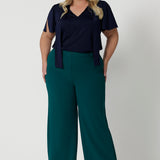 Full body front shot of plus sized woman wearing navy work wear blouse. This top is navy in colour and has been designed using high quality easy care dry touch jersey material. Garments are Australian made by Leina & Fleur for Australian and New Zealand woman. Leina & Fleur proudly stock sizes 8 through to 24. 