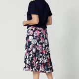 Back view of 40 year old woman wearing a dry touch jersey fabric skirt. 3/4 length skirt made from floral patterned fabric is very colourful with a combination of white and pink roses on navy base. This comfortable work wear skirt is great for both casual wear and dressed up for any occasion. This easy care skirt is made in Australia by Australian and New Zealand women. Leina & Fleur is a woman’s fashion label that stocks sizes from 8 to 24. Shop this comfortable skirt in plus size and petite sizes. 