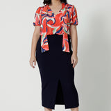 Full body front view of petite woman wearing a midi length work skirt that sits below the calves. This workwear skirt is navy and made of good quality fabric. This comfortable work skirt is stretchy and comfortable. Workwear skirt perfect or an office or corporate environment. 3/4 length skirt is Australian made. Leina & Fleur is a clothing brand for woman that have sizes from 8 to 24. Shop this work skirt in plus sizes and petite sizes. 