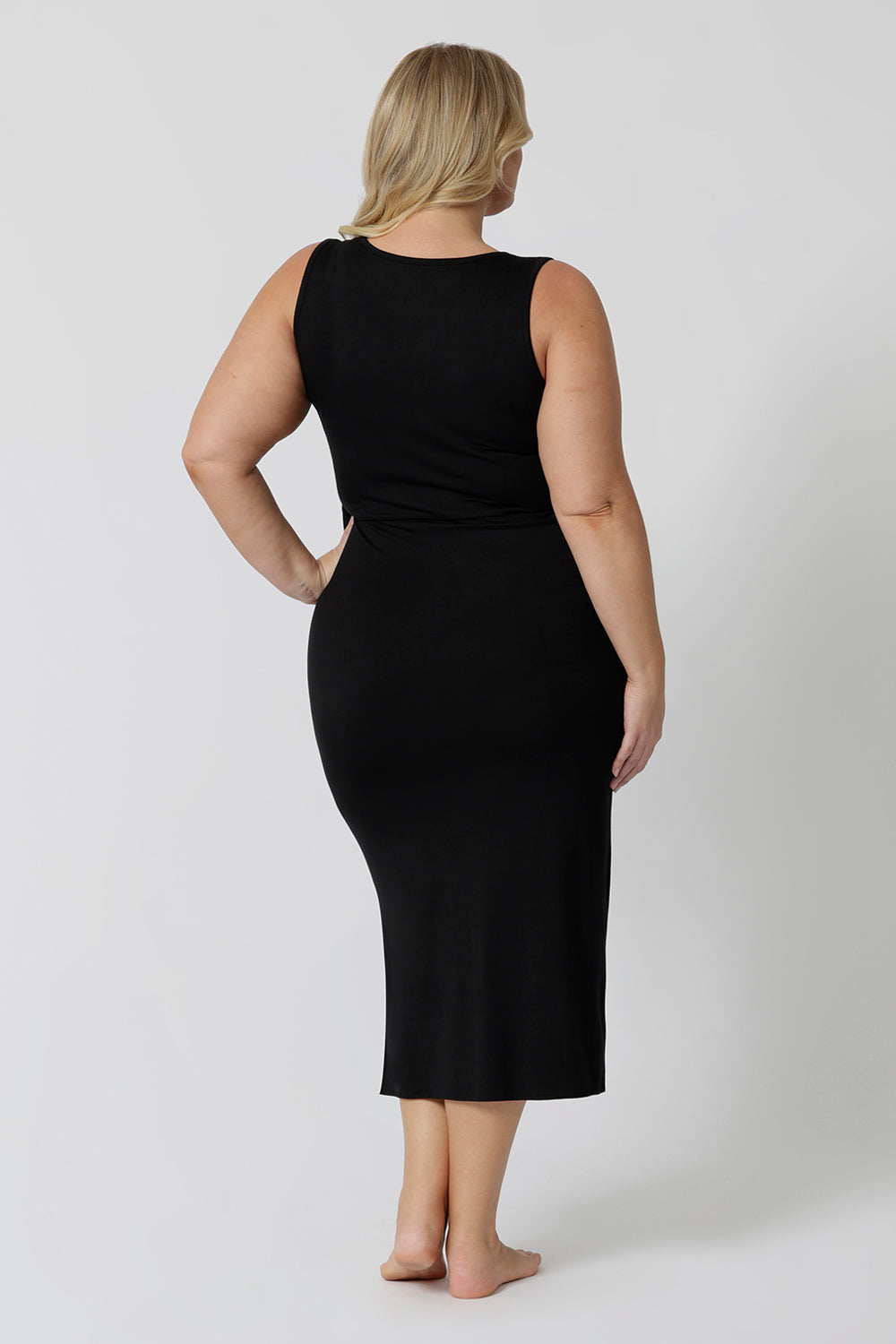 Back view of a midi dress that works as a nightdress and as loungewear. Shown on a size 18 woman, this slim-fit, plus size midi-dress in black bamboo jersey is breathable and thermo-regulating. A good dress for night sweats and hot flushes, wear this black dress as a summer dress for warm summer days. Shop nightdresses online in sizes 8 to 24 at L&F Australia.