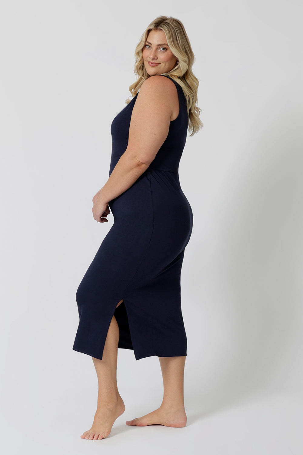 Side view of a midi dress that works as a nightdress and as loungewear. Shown on a size 18 woman, this slim-fit, plus size midi-dress in navy blue bamboo jersey is breathable and thermo-regulating. A good dress for night sweats and hot flushes, wear this as a summer dress for warm summer days. Shop nightdresses in women's clothes brand, L&F's new loungewear and sleepwear range online in sizes 8 to 24.