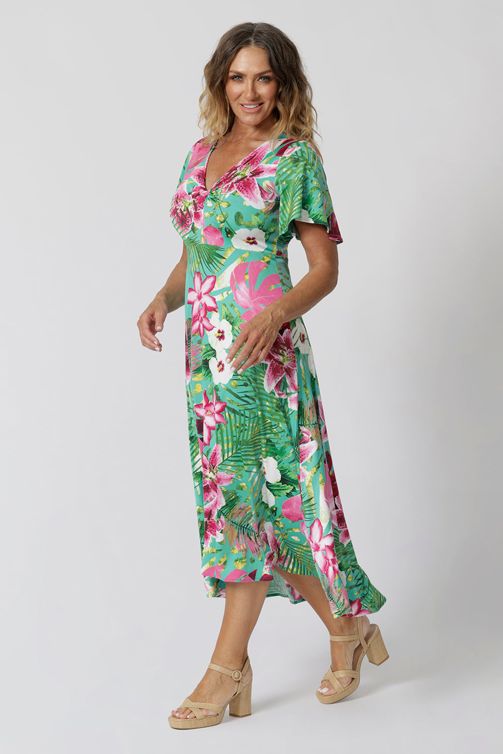 40 year old woman wears floral midi dress with twist bodice, flutter sleeve and high-low hem. This floral dress is made of slinky jersey making it perfect for beachside resorts, casual summer outings or easy resort style. Made in Australia by fashion brand Leina & Fleur stocked in sizes 8-24. 