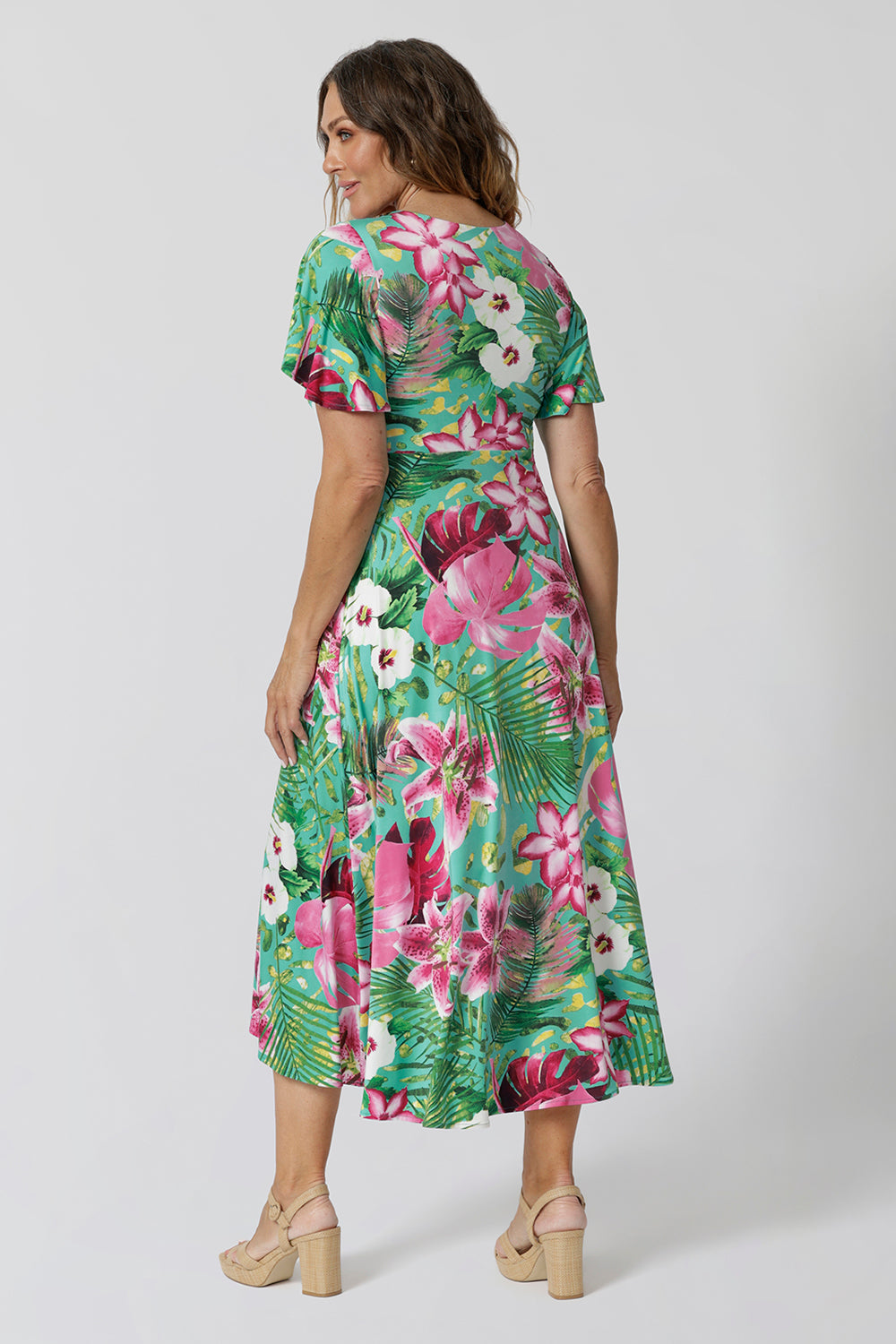 Back view of Milly Dress in Malibu detailing high-low hem and flutter sleeve. Midi length dress is made of floral slinky jersey fabric. Easy care dress is perfect for travel due to its wrinkle resistant features. Leina & Fleur proudly stocks sizes 8-24 including plus & petite friendly styles.