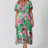 Image of 40 year old woman wears a floral midi length dress with twist bodice, flutter sleeve and high-low hem. Perfect dress for beachside resorts, casual summer outings or easy resort style. Made in Australia by fashion brand Leina & Fleur. Milly Dress in Malibu is stocked in sizes 8-24.