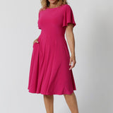 An image of a woman in her forties wearing a hot pink fit and flare dress made in Australia by Australian womenswear brand Leina & Fleur.