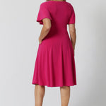 An image of the back of a woman in her forties wearing a hot pink fit and flare dress made in Australia by Australian womenswear brand Leina & Fleur.