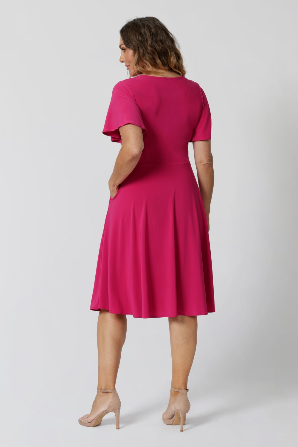 An image of the back of a woman in her forties wearing a hot pink fit and flare dress made in Australia by Australian womenswear brand Leina & Fleur.