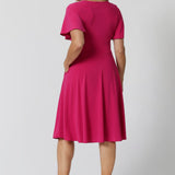 An image of the back of a woman in her forties wearing a hot pink fit and flare dress made in Australia by Australian womenswear brand Leina & Fleur.