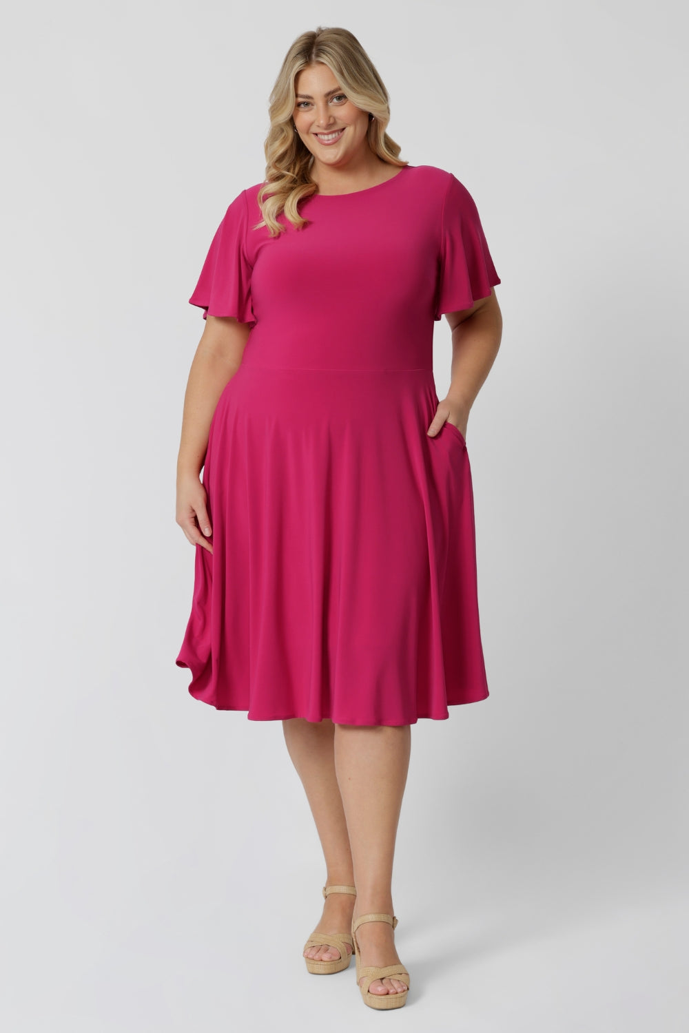 An image of a curve woman wearing a hot pink fit and flare dress made in Australia by Australian womenswear brand Leina & Fleur.