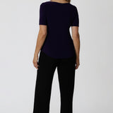 Back view of women's size inclusive work pants. Pictured on a size 12 woman these black comfortable corporate pants are worn with purple jersey top. Full length straight leg pants