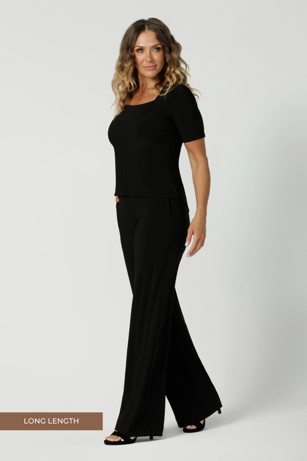 Over 40's model wears black pull on pants in long length. Classic black pants are a pull on style for easy care & wear. Leina & Fleur stock these pants in sizes 8-24 and in 3 height lengths.