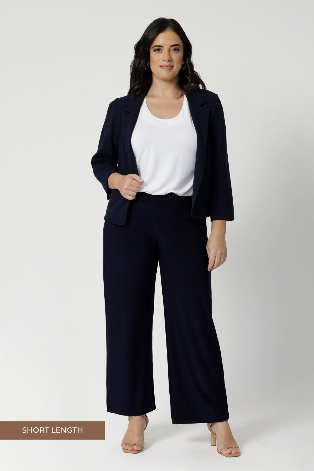 Navy workwear pants seen on size 10 petite height model, she wears short length Monroe pants with matching navy jacket and white top. Comfortable navy corporate pants are full length, straight leg pants with stretch. Shop in sizes 8-24.