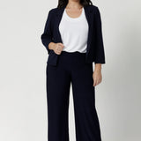 Navy workwear pants seen on size 10 petite height model, she wears short length Monroe pants with matching navy jacket and white top. Comfortable navy corporate pants are full length, straight leg pants with stretch. Shop in sizes 8-24.