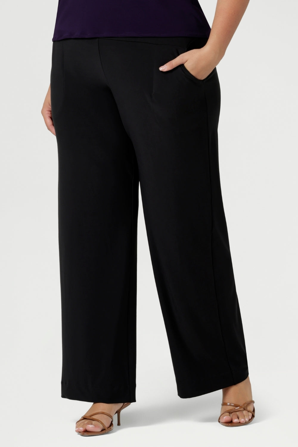 Close up image of black, stretchy workwear pant. Whether you're heading to the office or a professional event, the Monroe Pant ensures you look polished and feel at ease. Plus size woman wears her Monroe pants with brown kitten heel and straight hem top.