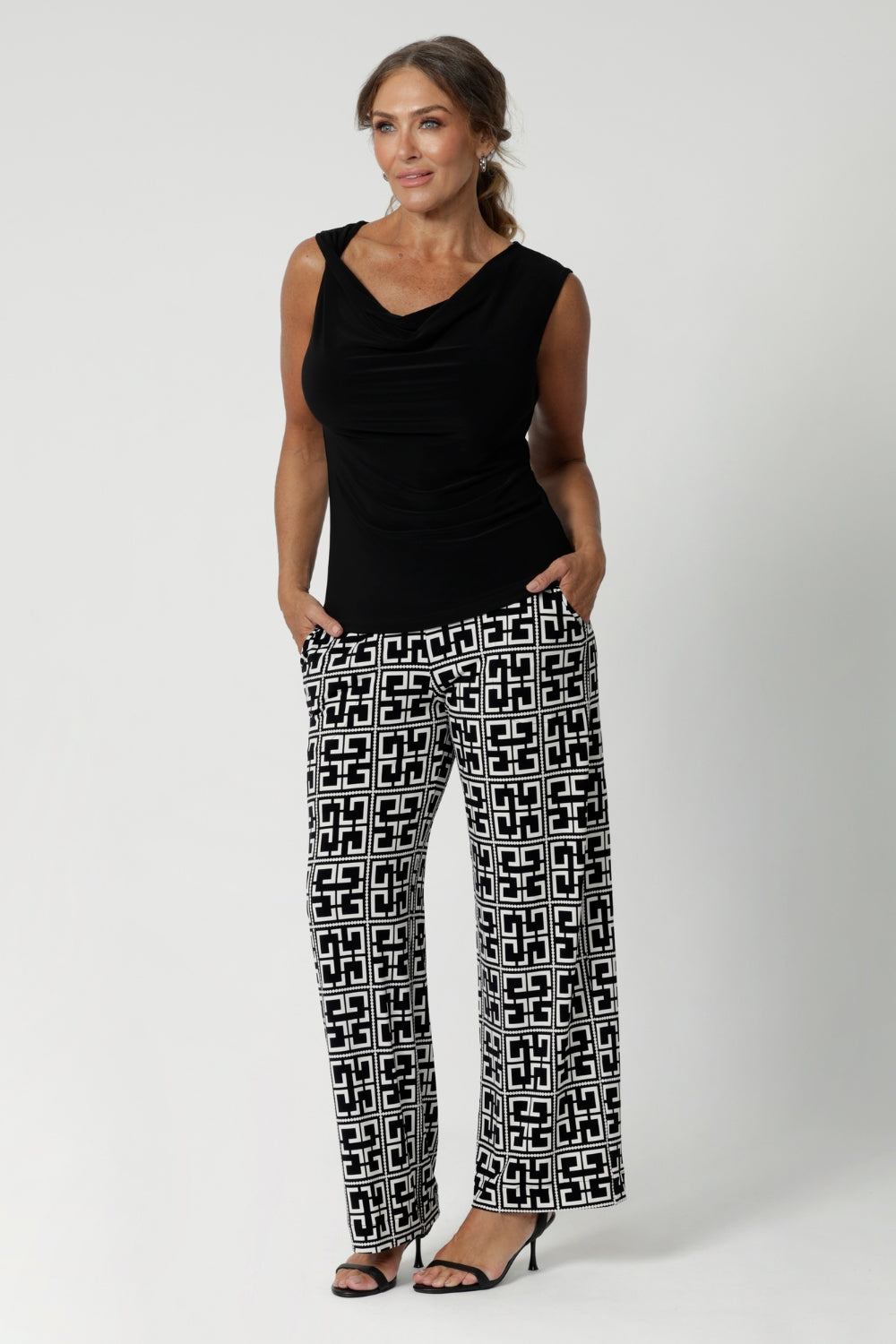 Made in Australia, the Monroe Pant combines versatility and sophistication, making them perfect for transitioning seamlessly from work to weekend. Over 40's woman wears printed pants with black workwear top and black heels.