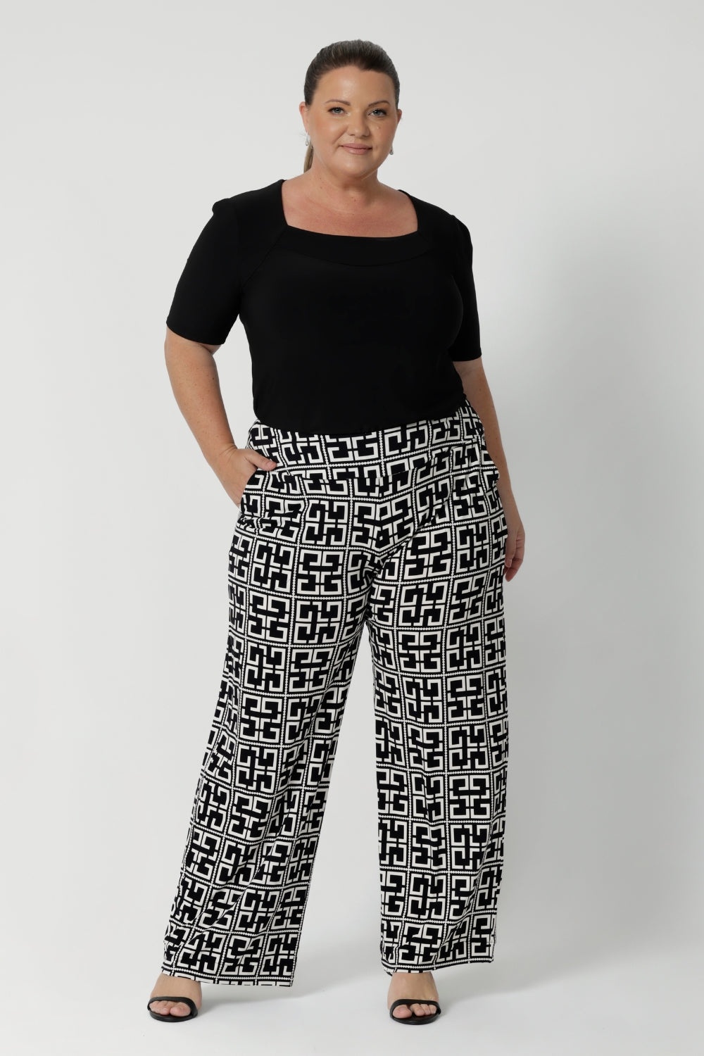 The Monroe Pant is designed to cater to various heights and comes in sizes 8-24, with the option of 3 pant lengths ensuring a great fit for all body types. Plus size woman wears regular length Monroe Pants with black top and heels.