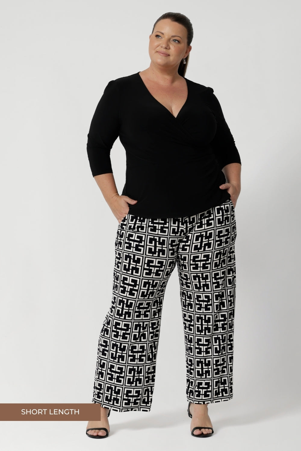 Size 18 model wears long length Monroe Pants in Olympia print with black fixed wrap top and black heels, creating an outfit that is perfect for the corporate woman on the go. Available in sizes 8-24, with the option of 3 pant lengths. 