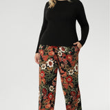 Monroe Pant effortlessly transitions from work to weekend with ease. Made in Australia, these pants combine sophistication and practicality. Tall woman wears floral printed pants with black work top. Size 18 model wears long length Monroe Pants. 