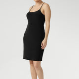 Woman wears a mini-length, reversible slip in black jersey fabric. The slip has thin straps and is worn with a V neck to the front. Made in Australia to layer under dresses and separates. Dress slips for women. Available in size 8-24.