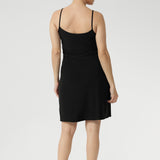 Woman wearing a black slip dress on a white background barefoot. Designed to wear as loungewear or to layer under dresses and separates, Myah is a fully reversible slip, perfect as a base layer to wear under dresses or separates for smooth, comfortable coverage. 