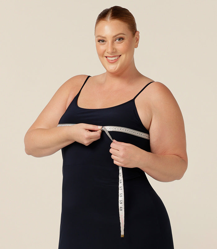 A plus size woman in a black slip with a tape measure showing how to find your perfect size in L&F's new evening dress and cocktail attire collection. 