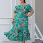  Plus sized woman wears the Myla dress in Jade Safari off the shoulders - a jade coloured dress with abstract animal print design. Maxi dress features side pockets and frill hem. Made in Australia and size inclusive for women size 8-24. 